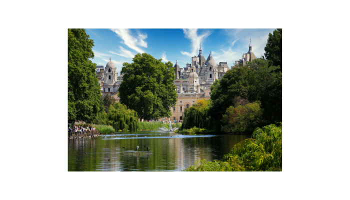 Peaceful lake and greenery inside St James’s Park with historic London buildings in the background.