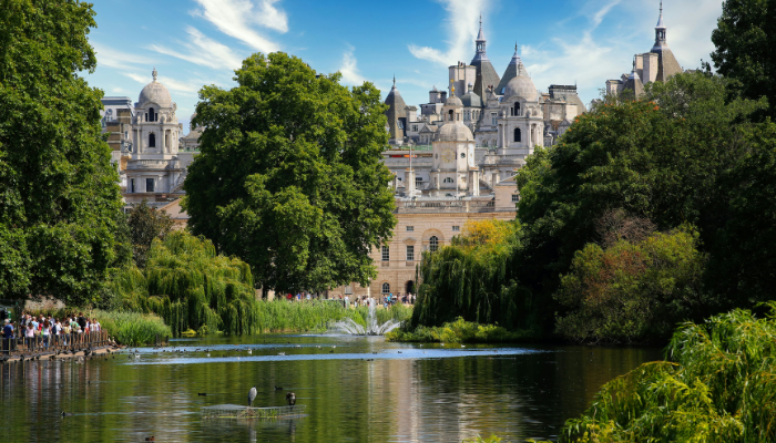 Peaceful lake and greenery inside St James’s Park with historic London buildings in the background.