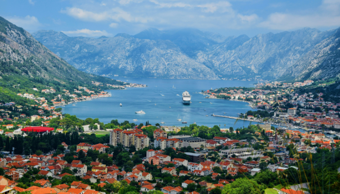 Panoramic view of Kotor Bay in Montenegro with cruise ships, coastal town, and surrounding mountains.