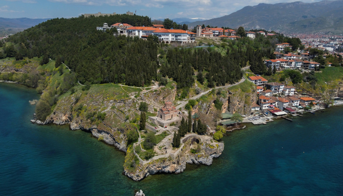 Lake Ohrid in North Macedonia with historic church on cliff, clear blue water, and lakeside village.