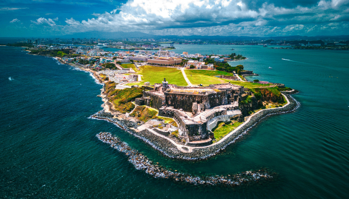 Aerial view of Old San Juan and its historic coastal fort surrounded by bright blue Caribbean waters in Puerto Rico.