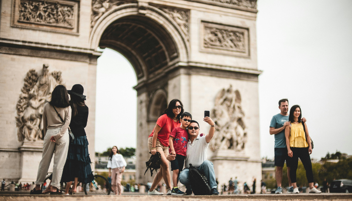 Tourists taking photos near the Arc de Triomphe in Paris, one of the city’s must-visit landmarks for first-time travelers.