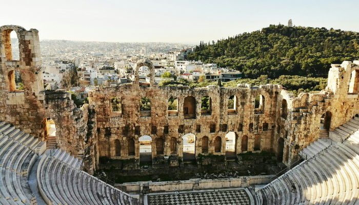Interior of the ancient Odeon of Herodes Atticus amphitheatre with Athens city and green hills beyond.