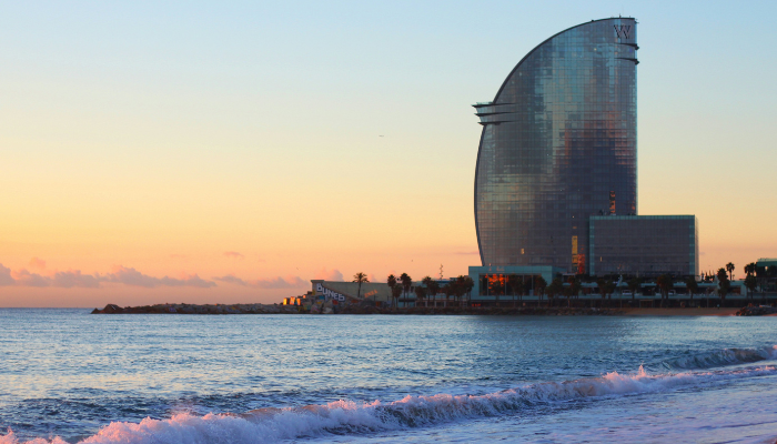 Sunset view of the W Barcelona Hotel along Barceloneta Beach, overlooking the Mediterranean Sea and waterfront promenade.