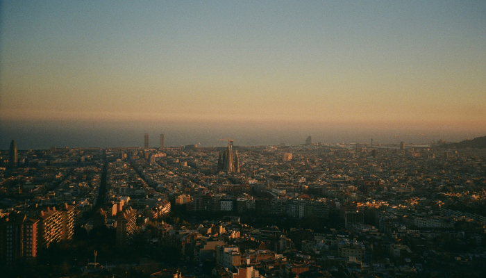 Panoramic sunset view of Barcelona from Bunkers del Carmel, with Sagrada Família rising above the city's grid-like streets.