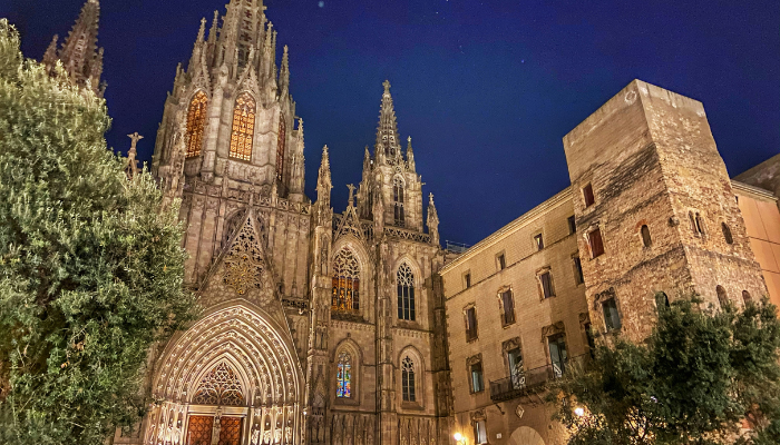 Barcelona Cathedral illuminated at night, showcasing its Gothic façade and intricate architectural details in the historic city center.