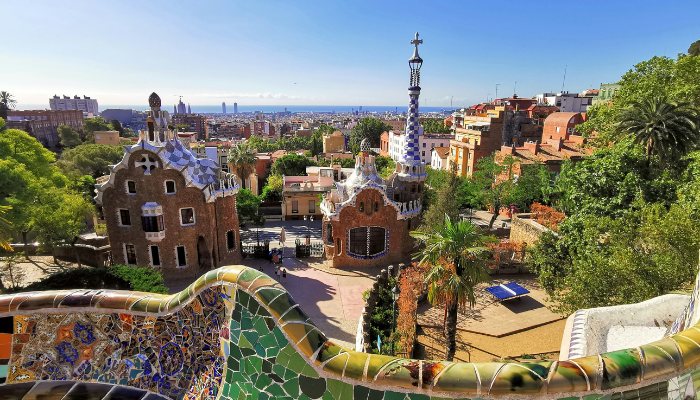 Colorful mosaic terrace and whimsical architecture at Park Güell, offering panoramic views over Barcelona.