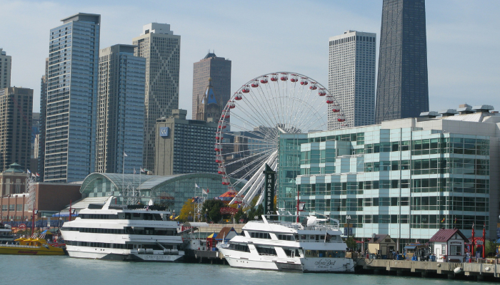 Cruise vessels docked near Navy Pier with Chicago's skyline and Centennial Wheel in the background, a popular departure point for boat tours.