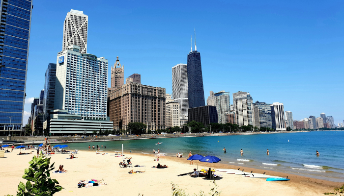 Visitors relaxing on Oak Street Beach with Chicago's skyline rising behind Lake Michigan, one of the city's most scenic waterfront views.
