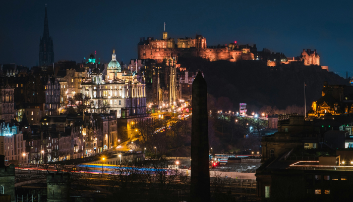 Night view of Edinburgh city centre with illuminated Edinburgh Castle overlooking the historic skyline.