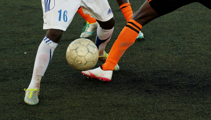 Close up of two football players battling for possession of the ball during a soccer match.
