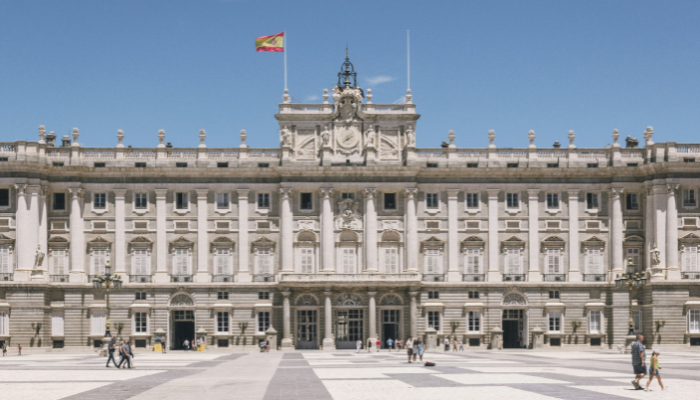 Royal Palace of Madrid façade viewed from the Plaza de la Armería on a sunny day.
