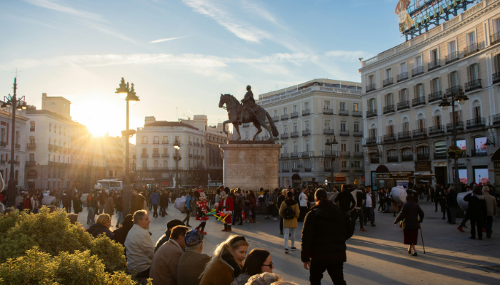 Crowds gathering around the equestrian statue in Puerta del Sol Madrid at sunset.
