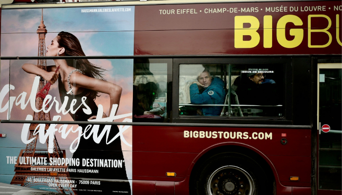 A hop-on hop-off Paris sightseeing bus passing through the city, offering a convenient way to travel between Paris' top museums and attractions.