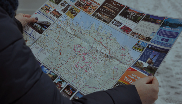 Traveler using a city map to plan an Athens sightseeing itinerary before boarding a hop-on hop-off bus tour.