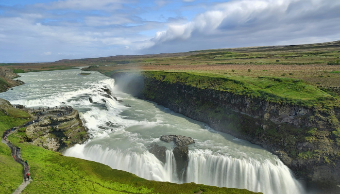 Gullfoss Waterfall on Iceland's Golden Circle route with powerful cascades flowing through a dramatic green canyon.