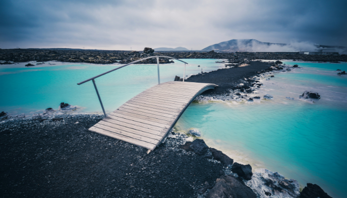 Blue Lagoon geothermal spa with turquoise water, black lava rocks and a wooden walkway in Iceland