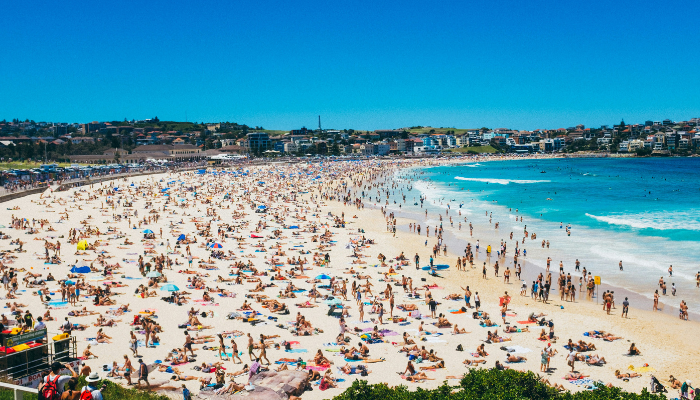 Crowds enjoying the sand and surf at Bondi Beach, a popular stop on the Sydney hop-on hop-off bus Bondi route.