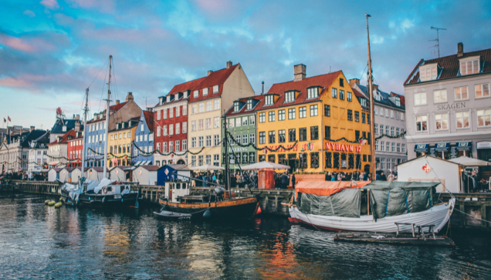 Colourful Nyhavn waterfront with historic buildings, boats and reflections along the canal in Copenhagen.
