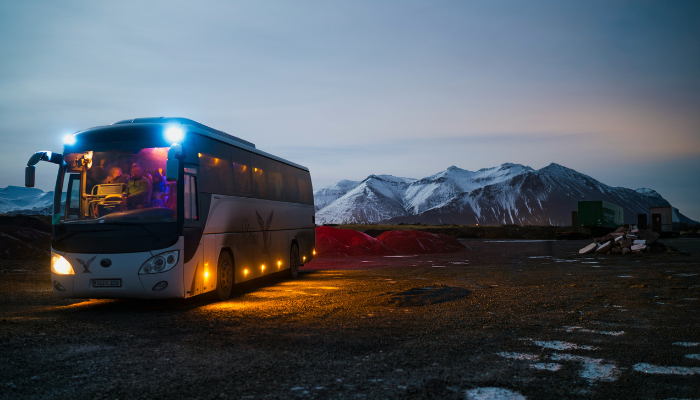 Tour bus parked against a snowy Icelandic mountain landscape