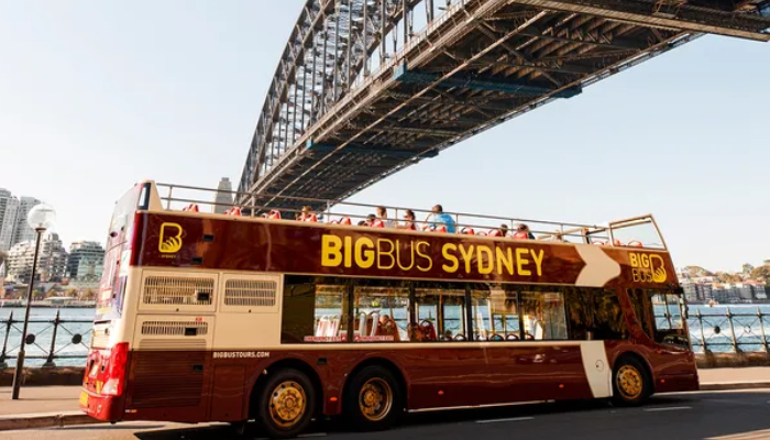 Big Bus Sydney hop-on hop-off sightseeing bus passing beneath the Sydney Harbour Bridge near Circular Quay.