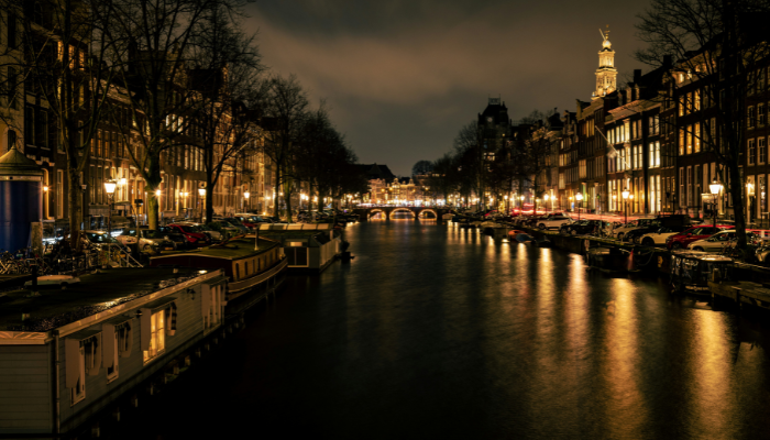 Amsterdam canals illuminated at night with historic buildings, houseboats and reflections on the water