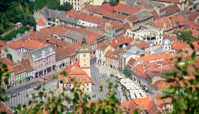 Aerial view of Brașov’s historic old town in Romania, with red-roofed buildings and the Council Square