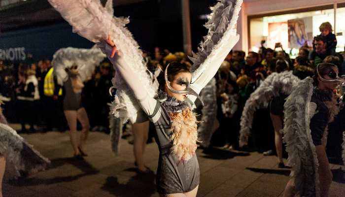 Halloween parade featuring a costumed angel performer with white wings in Dublin