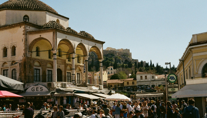 Busy Plaka street in Athens with cafes, shops and the Acropolis visible in the distance