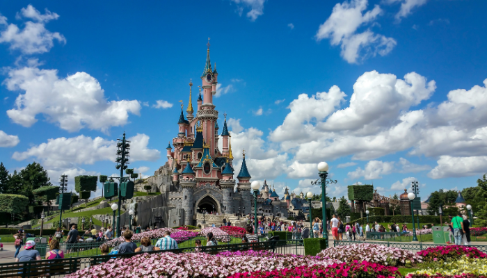 Sleeping Beauty Castle at Disneyland Paris surrounded by colourful flower beds and visitors