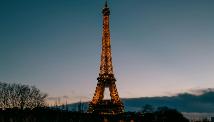 Eiffel Tower illuminated at dusk against a fading blue sky in Paris