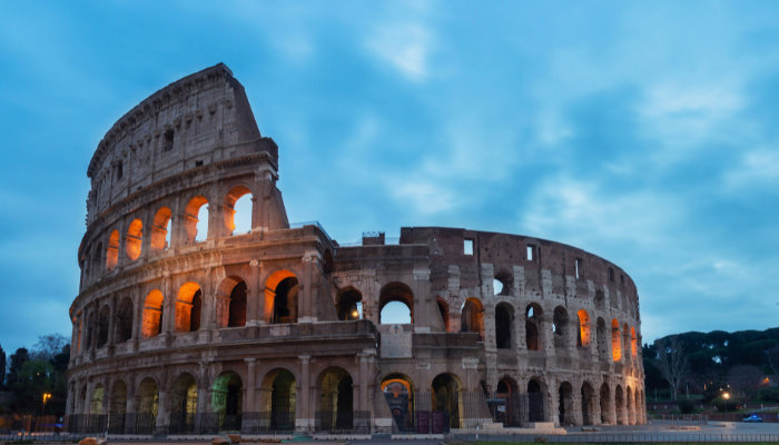 Rome Colosseum illuminated at dusk against a blue evening sky