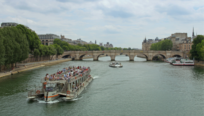 Sightseeing boat cruising along the Seine River past historic bridges in Paris